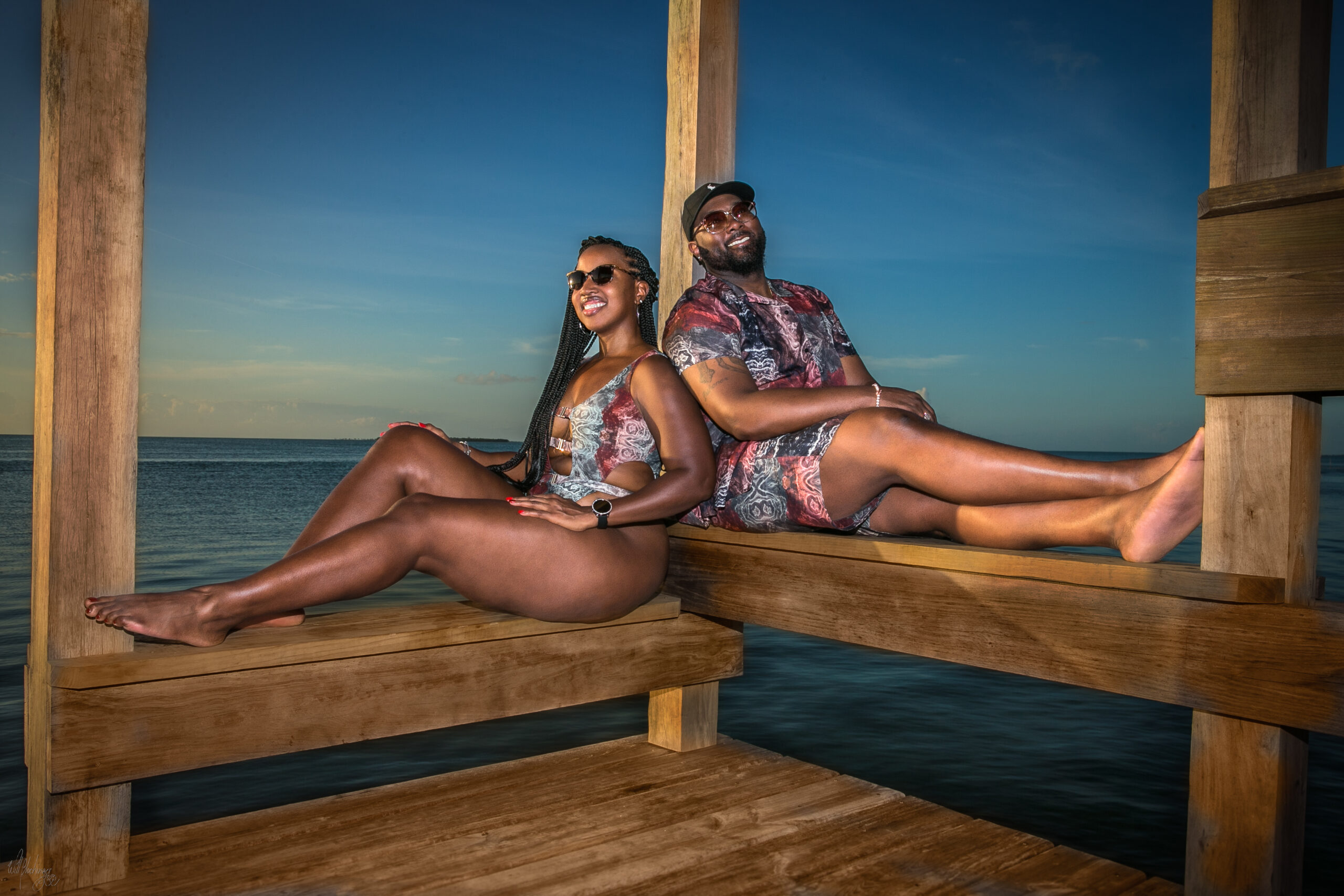 Couple posing on a boathouse pier over the Caribbean Sea at sunset in San Pedro Belize photographed by San Pedro Belize photographer Will Blochinger